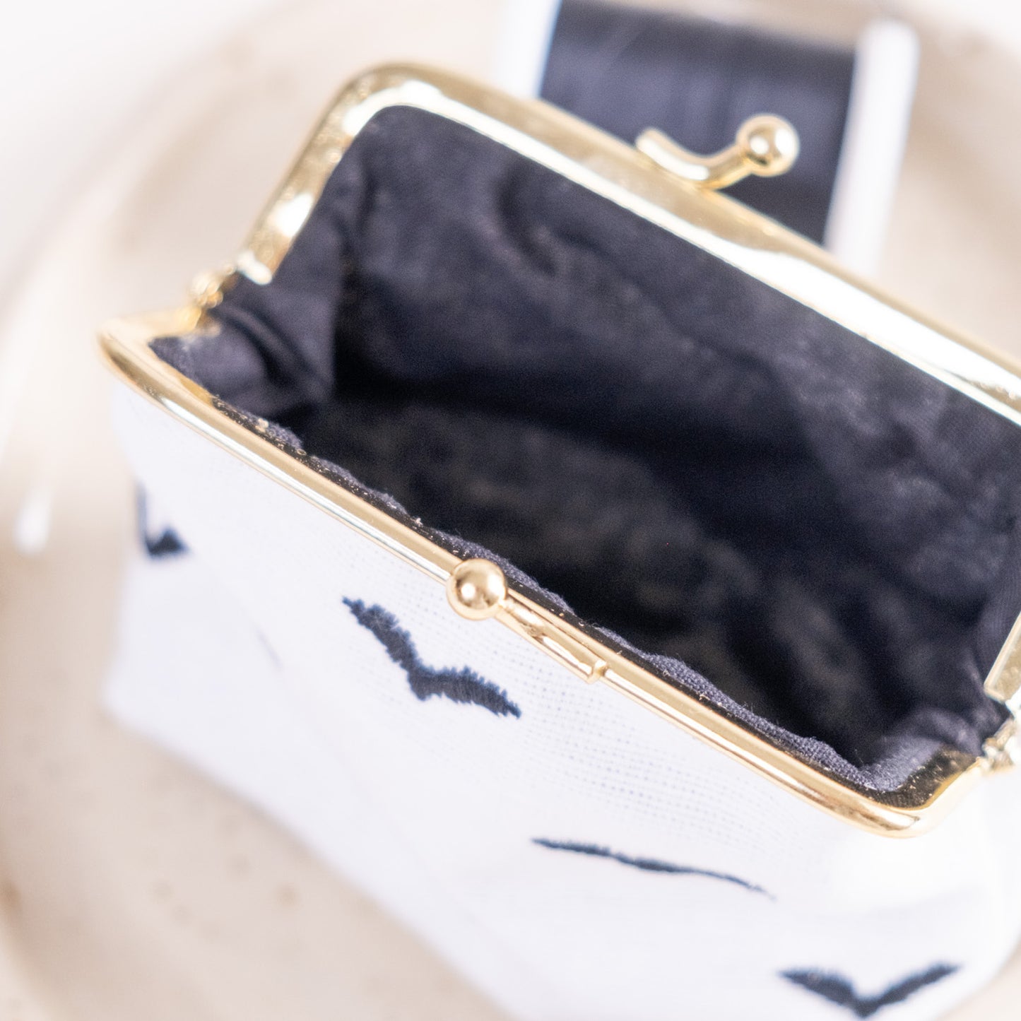 Torbica s kovinskim zapiranjem in izvezenimi netopirji