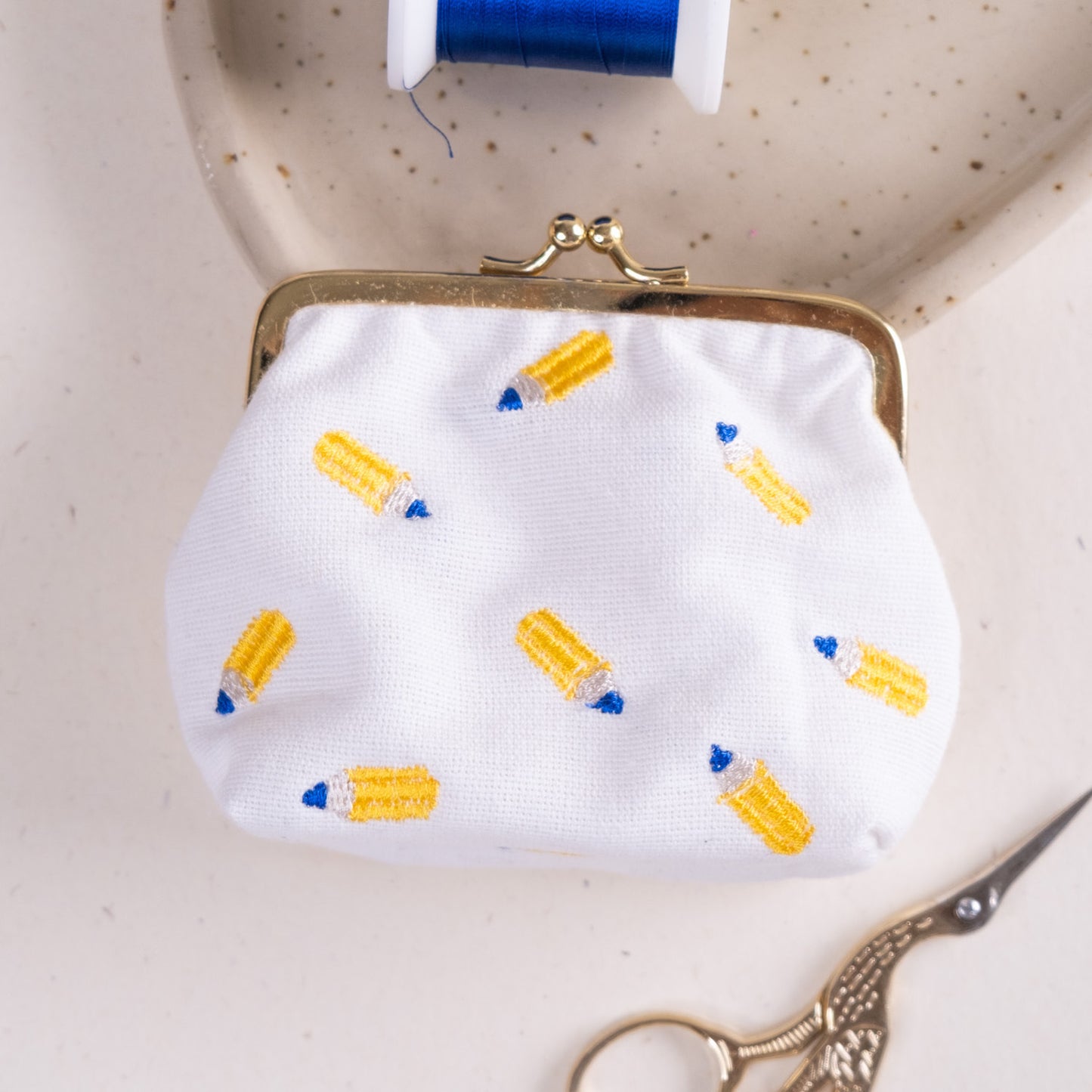 Torbica s kovinskim zapiranjem in izvezenimi svinčniki