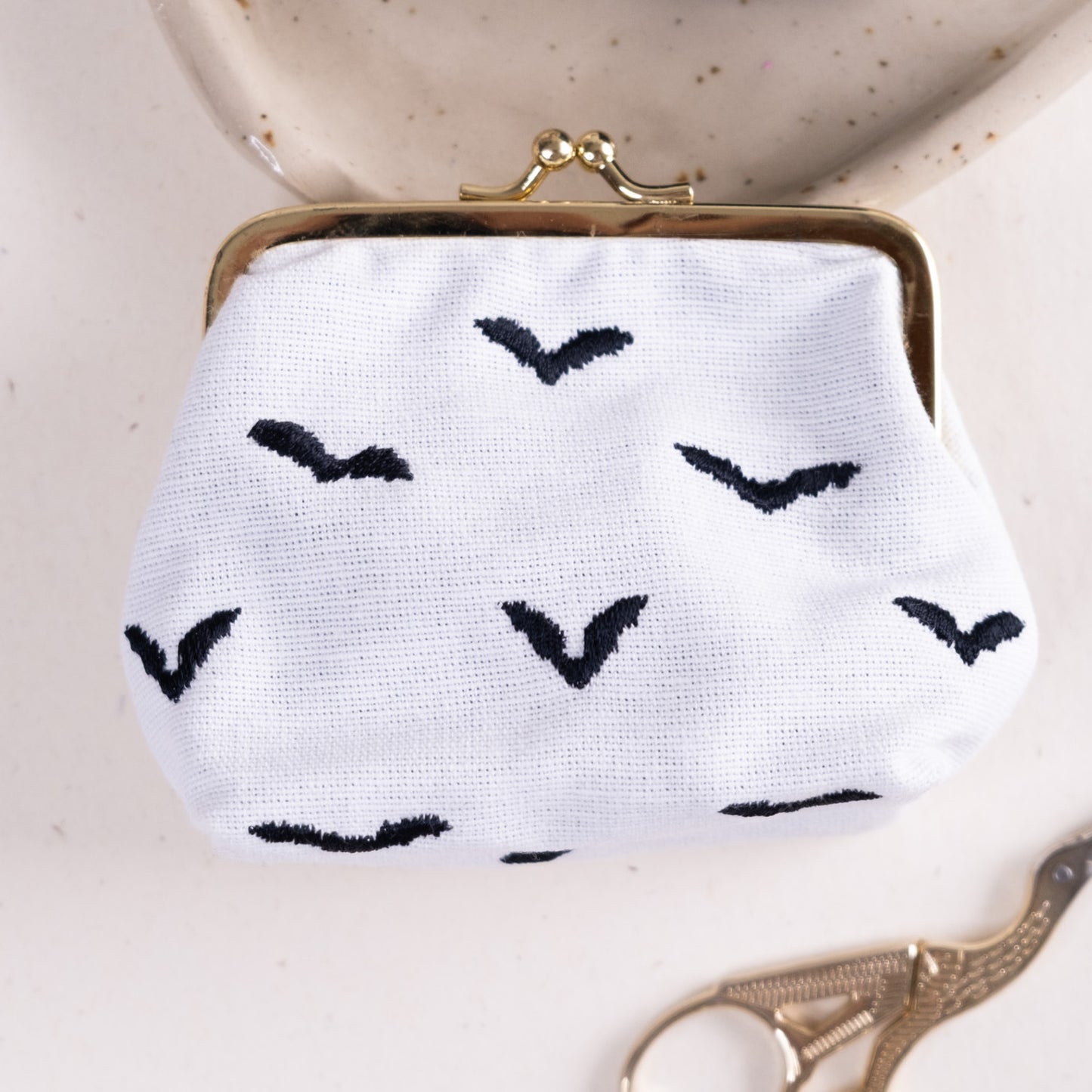 Torbica s kovinskim zapiranjem in izvezenimi netopirji