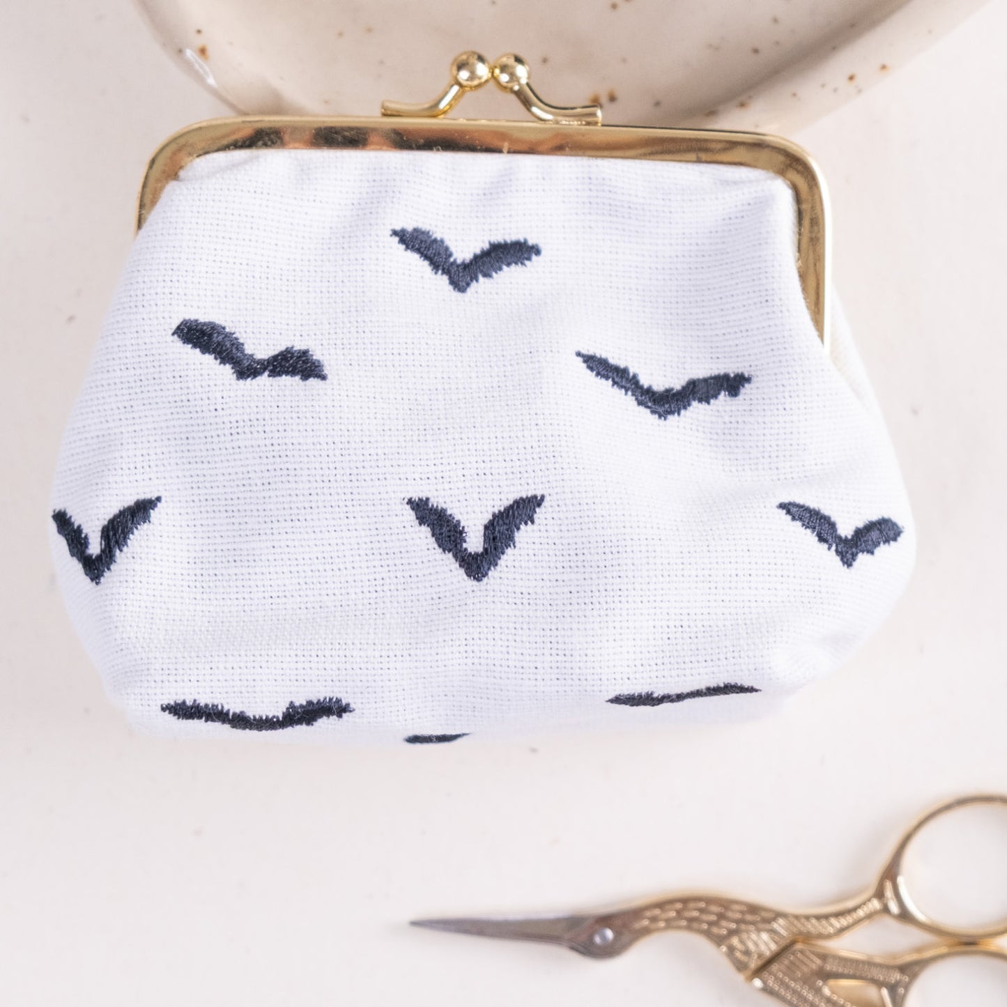 Torbica s kovinskim zapiranjem in izvezenimi netopirji